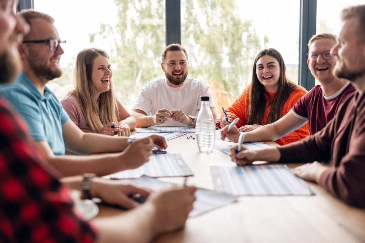 Sport-Thieme Mitarbeitende spielen in der Mittagspause gemeinsam Stadt, Land, Fluss, lachen und tauschen sich aus.