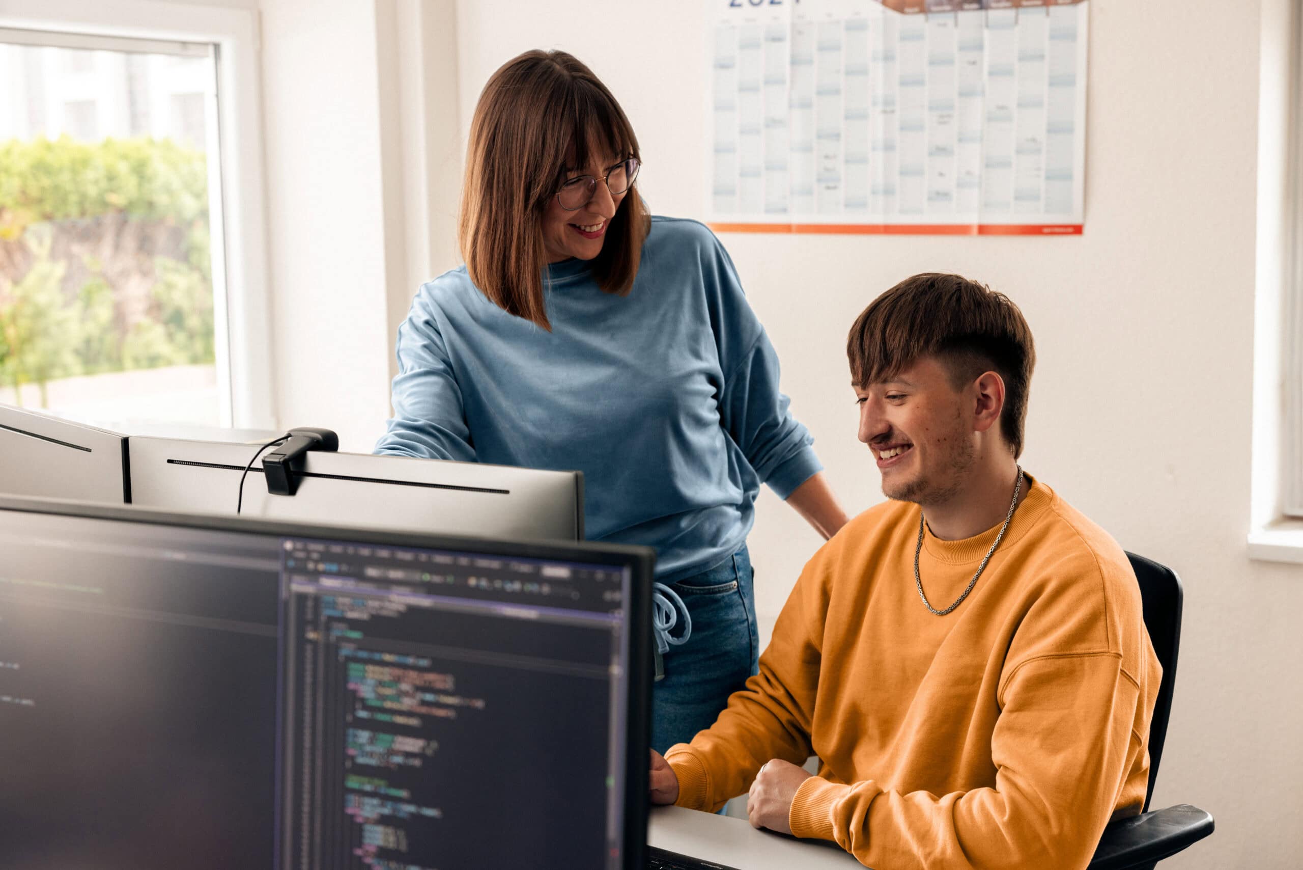 Software development trainee discussing with a colleague.