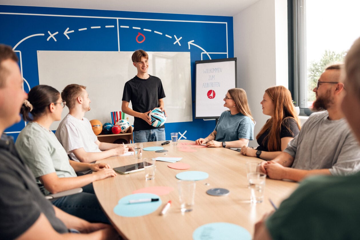 Apprentices engage in conversations during the trainee meeting.