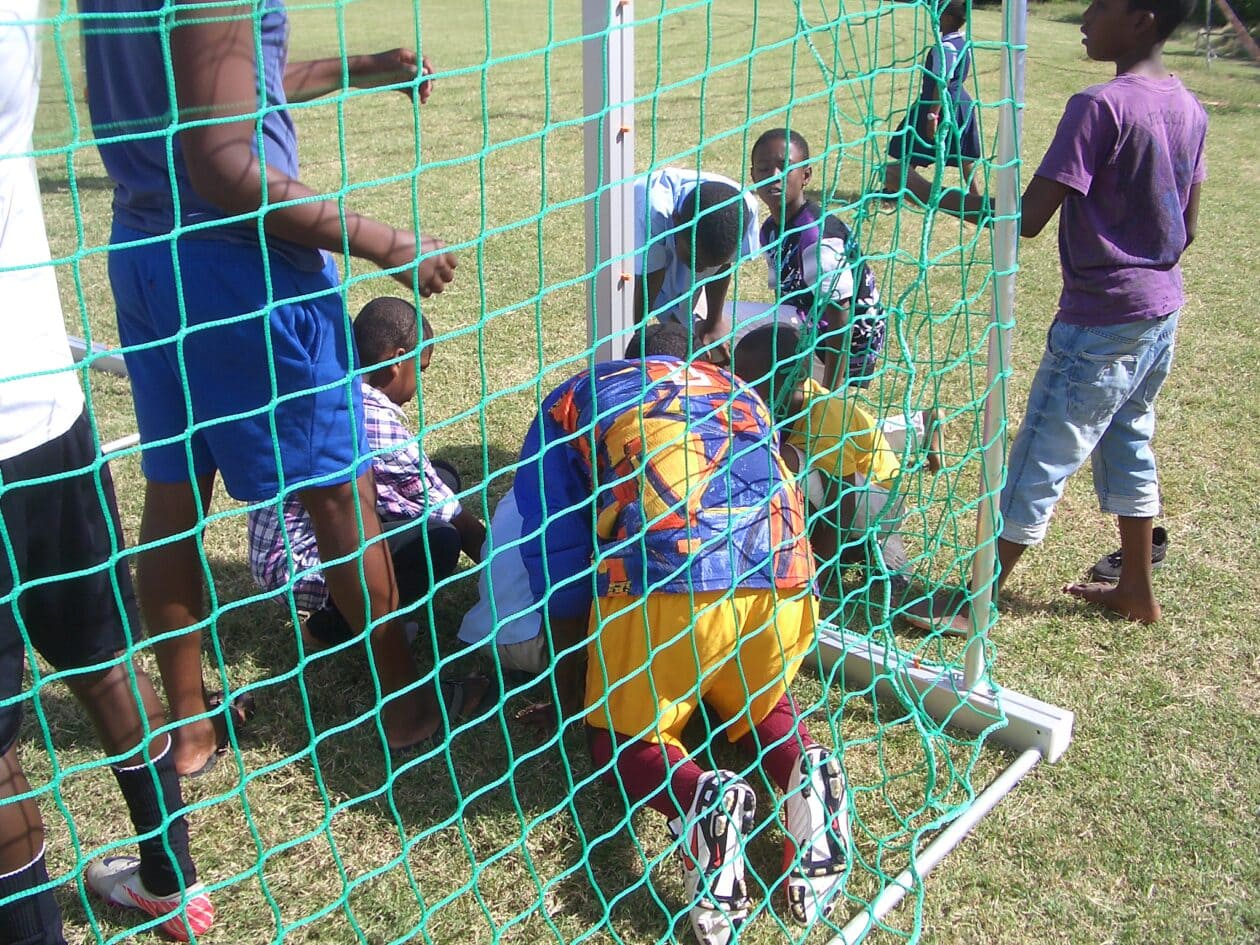 Children from barbados sitting in a goal