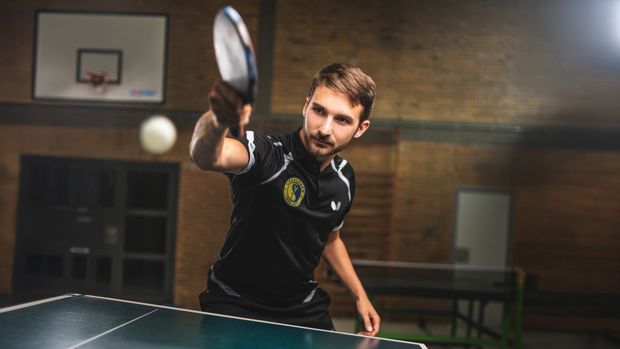 Man focused on playing table tennis indoors.