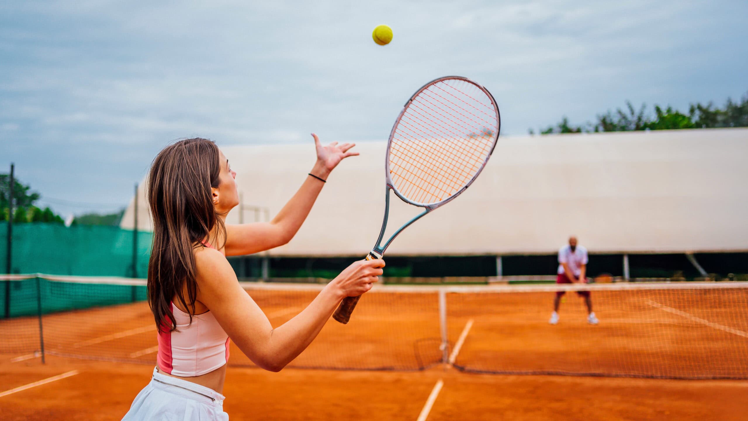 Tennisspielerin bereitet Aufschlag auf Sandplatz vor.