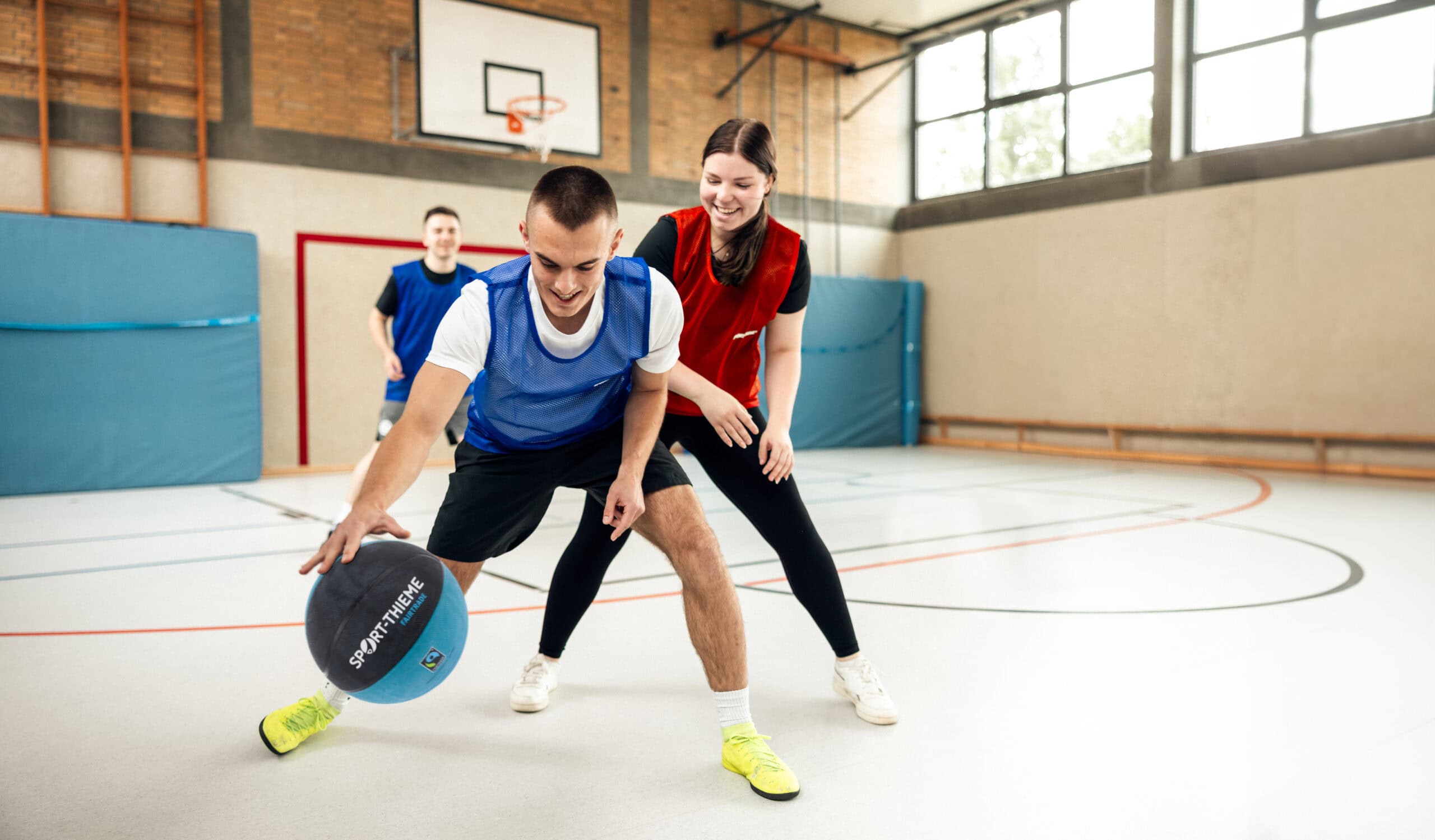 Sport-Thieme trainees playing basketball in a gym.
