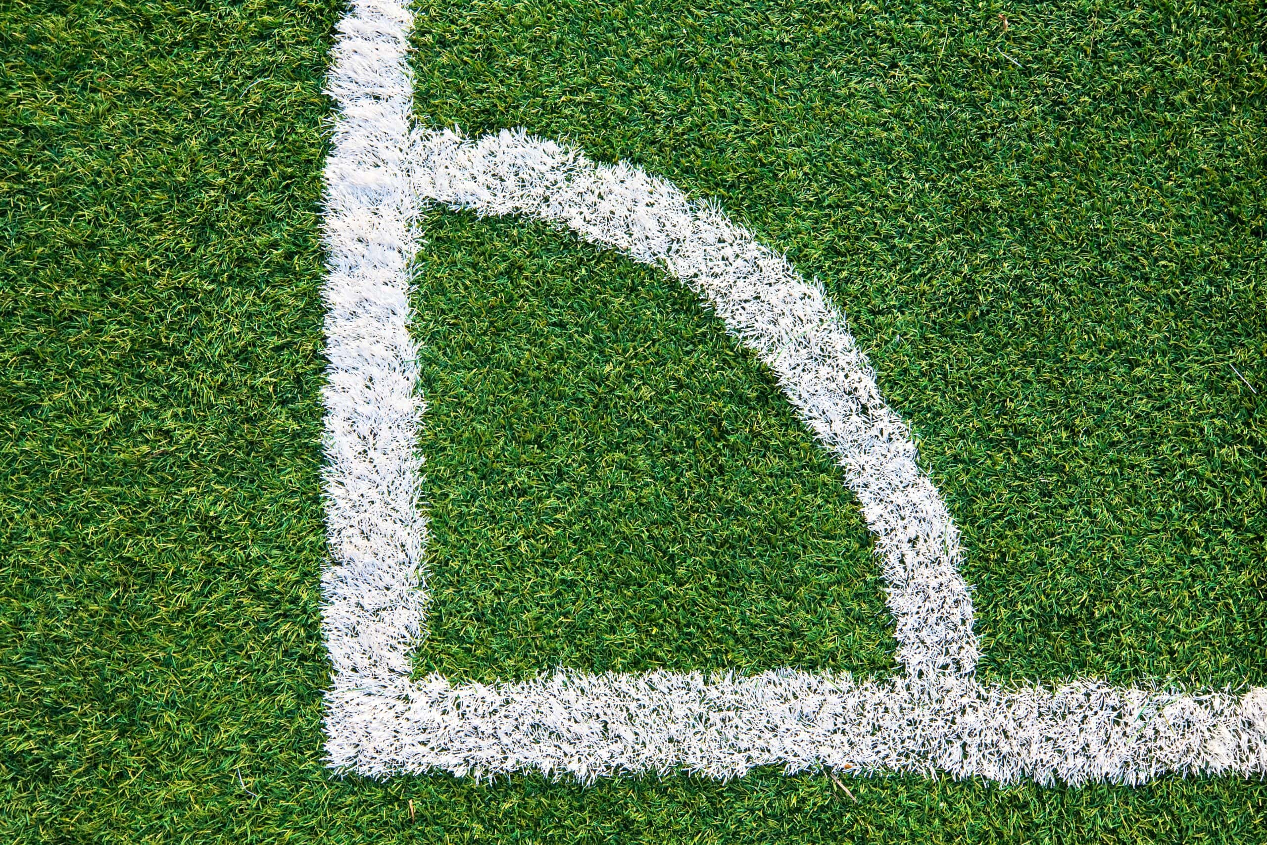Close-up of a white corner marking on an artificial turf football field.